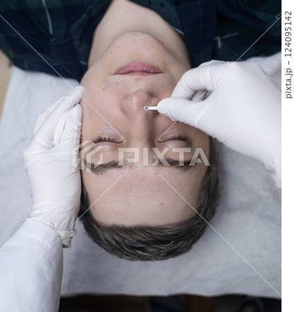 Man undergoing facial cleansing and blackhead removal. Beautician using comedone extractor or uno loop. Professional skin care in a beauty salon 124095142