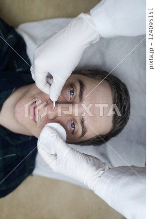 Man undergoing facial cleansing and blackhead removal. Beautician using comedone extractor or uno loop. Professional skin care in a beauty salon Man undergoing facial cleansing and blackhead removal. Beautician using comedone extractor or uno loop. Professional skin care in a beauty salon 124095151