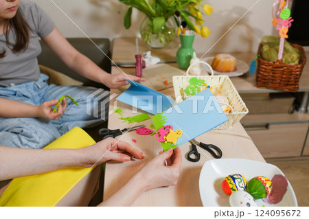 Mother and daughter creating Easter greeting cards with colorful felt cutouts. Mother and daughter creating Easter greeting cards with colorful felt cutouts. 124095672