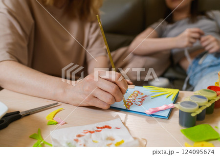 Close-up of a woman painting Happy Easter on a handmade greeting card. Close-up of a woman painting Happy Easter on a handmade greeting card. 124095674