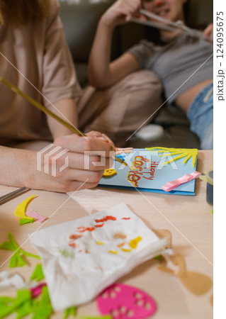Close-up of a woman painting Happy Easter on a handmade greeting card. Close-up of a woman painting Happy Easter on a handmade greeting card. 124095675