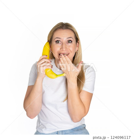 Young blonde beautiful woman holding banana. Blond woman in white t-shirt hold bananas on white background Young blonde beautiful woman holding banana. Blond woman in white t-shirt hold bananas on white background 124096117