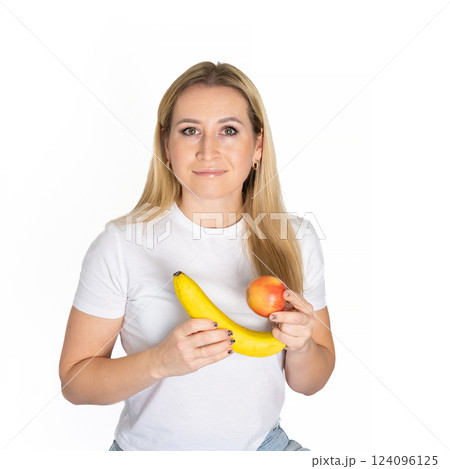 Young blonde beautiful woman holding apple and banana. Blond woman in white t-shirt hold apple and banana on white background 124096125