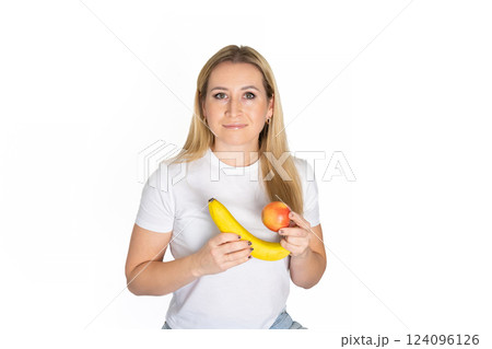 Young blonde beautiful woman holding apple and banana. Blond woman in white t-shirt hold apple and banana on white background 124096126
