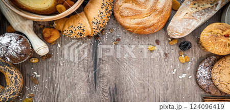 Bakery - various kinds of breadstuff. Bread rolls, baguette, bagel, sweet bun and croissant captured from above (top view, flat lay). wooden rustic background, copy space. Horizontal banner layout. Bakery - various kinds of breadstuff. Bread rolls, baguette, bagel, sweet bun and croissant captured from above (top view, flat lay). wooden rustic background, copy space. Horizontal banner layout. 124096419