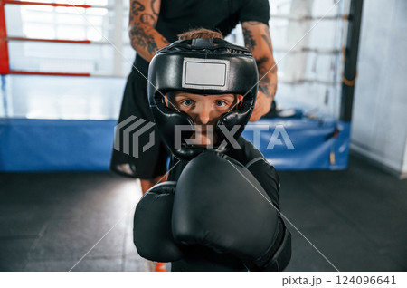 In protective helmet. Coach is teaching the boy box techniques indoors 124096641