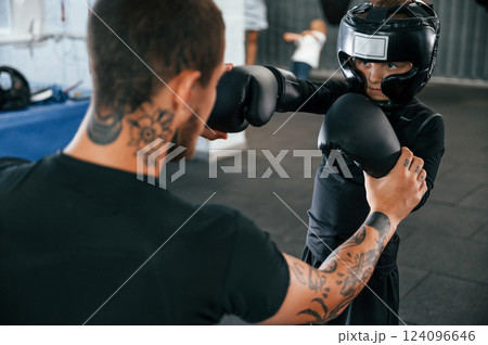 In protective helmet. Coach is teaching the boy box techniques indoors 124096646