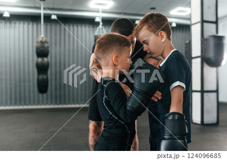 Preparing for the sparring. Young tattooed coach teaching the kids boxing techniques 124096685