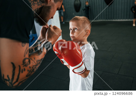 Preparing for the sparring. Coach is teaching the boy box techniques indoors Preparing for the sparring. Coach is teaching the boy box techniques indoors 124096686