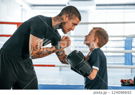 Giving advices. Coach is teaching the boy box techniques indoors 124096692