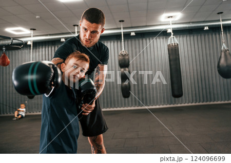 Giving advices. Coach is teaching the boy box techniques indoors 124096699
