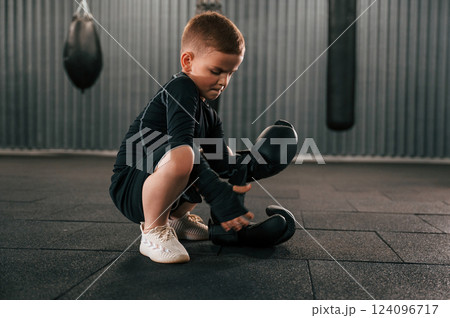 Wearing the glowes. Boy is practicing boxing in the gym 124096717
