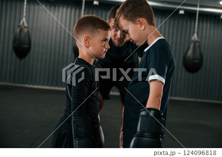 Preparing for the sparring. Young tattooed coach teaching the kids boxing techniques 124096818