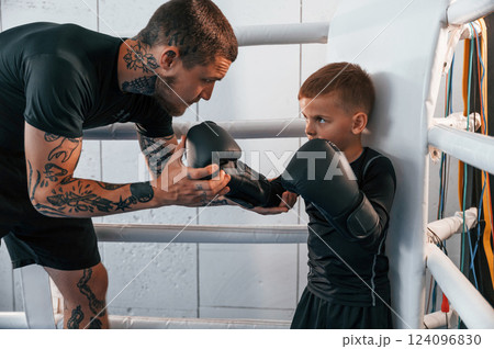 Together on the ring. Coach is teaching the boy box techniques indoors Together on the ring. Coach is teaching the boy box techniques indoors 124096830