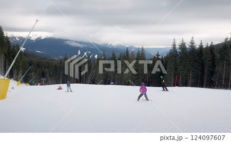 People skiing on the snowy slope of Bukovel ski resort in the Ukrainian Carpathian mountains. 124097607