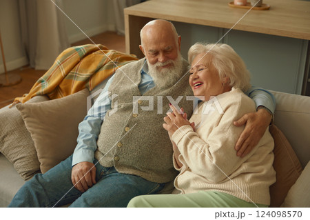 Smiling happy elderly couple feeling love and bonding hugging on sofa 124098570