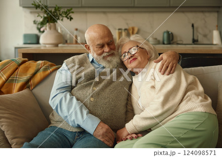Happy retired couple feeling love and bonding hugging on sofa 124098571