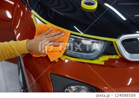 Man technician rubbing surface headlamps with microfiber cloth closeup Man technician rubbing surface headlamps with microfiber cloth closeup 124098589