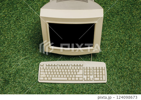 Vintage PC on green grass, top view. Monitor and keyboard as in 90s 124098673