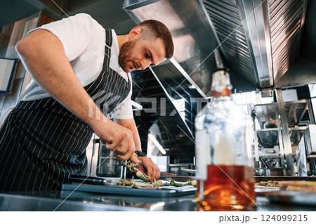 Slicing and cutting asparagus. Chef is on the kitchen preparing food Slicing and cutting asparagus. Chef is on the kitchen preparing food 124099215