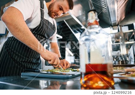 Slicing and cutting asparagus. Chef is on the kitchen preparing food 124099216