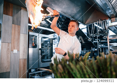 Flaming the chicken meat. Chef is on the kitchen preparing food 124099311