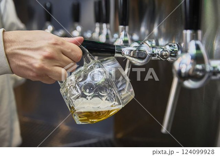A hand holds a mug of beer in a self-service beer bar A hand holds a mug of beer in a self-service beer bar 124099928