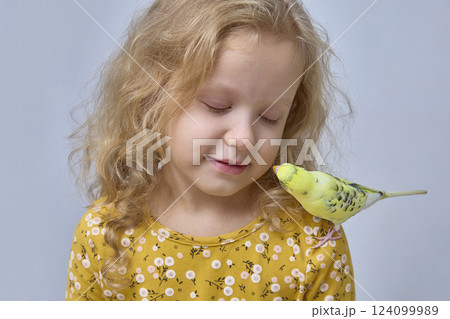 A child plays with a budgie. Interaction between children and pets 124099989