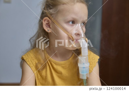 The sick girl is breathing and being treated with a nebulizer. 124100014