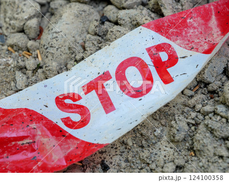 Caution tape lies on dirt by a construction site. Caution tape lies on dirt by a construction site. 124100358