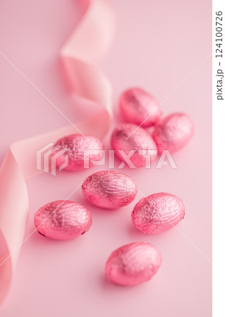 Chocolate easter eggs wrapped in pink colored foil on pink background. Chocolate easter eggs wrapped in pink colored foil on pink background. 124100726