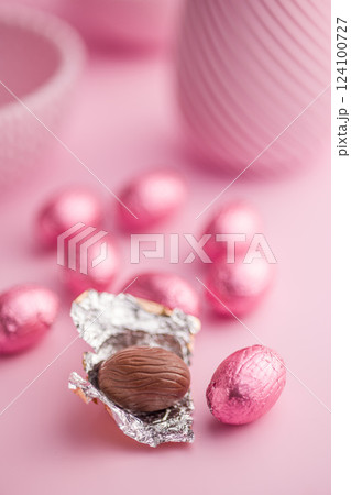 Chocolate easter eggs wrapped in pink colored foil on pink background. 124100727