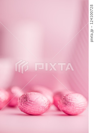 Chocolate easter eggs wrapped in pink colored foil on pink background. 124100728