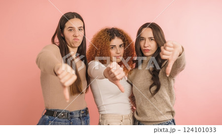 Three women expressing disapproval with thumbs down 124101033