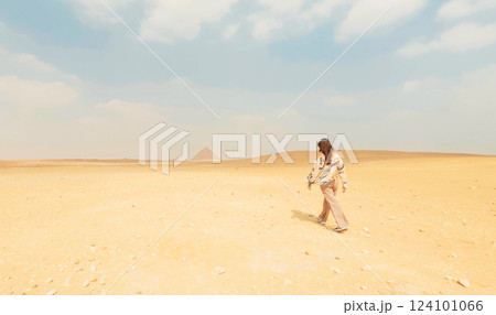 Tourist walking in the desert towards the pyramids of giza Tourist walking in the desert towards the pyramids of giza 124101066
