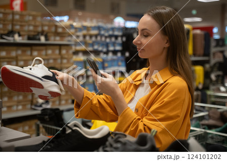 Woman scans shoes while shopping in a retail store for styles and sizes during a weekend visit Woman scans shoes while shopping in a retail store for styles and sizes during a weekend visit 124101202