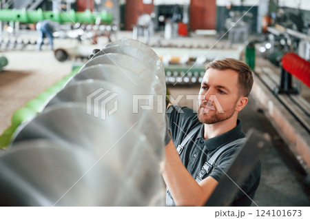 Checking slicing parts. Man in uniform is in workstation developing details of agriculture technique 124101673