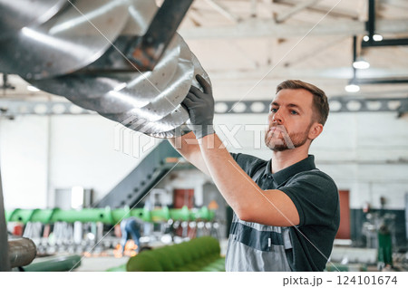 Checking slicing parts. Man in uniform is in workstation developing details of agriculture technique 124101674