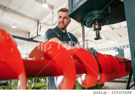 Attention to detail. Man in uniform is in workstation developing parts of agriculture technique 124101686