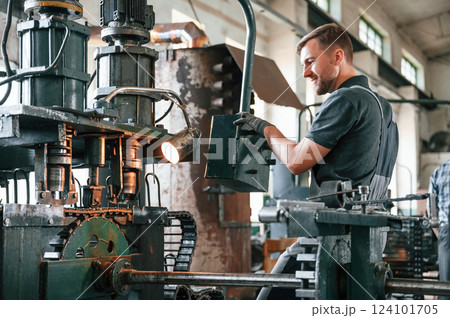 Metal processing device. Man in uniform is in workstation developing details of agriculture technique Metal processing device. Man in uniform is in workstation developing details of agriculture technique 124101705