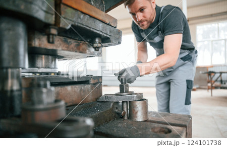 Operating manufacturing equipment. Man in uniform is in workstation developing details of agriculture technique 124101738