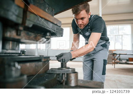 Operating manufacturing equipment. Man in uniform is in workstation developing details of agriculture technique 124101739