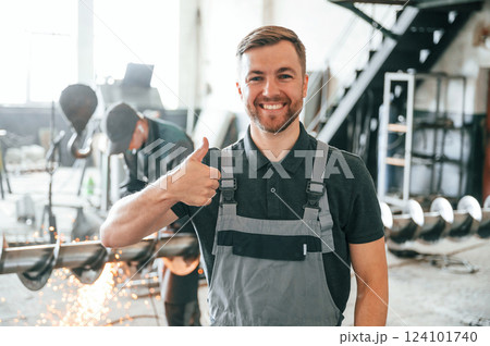 Standing and smiling. Man in uniform is in workstation developing details of agriculture technique 124101740