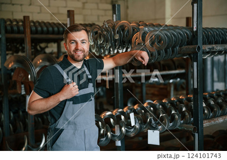 Standing and smiling. Man in uniform is in workstation developing details of agriculture technique Standing and smiling. Man in uniform is in workstation developing details of agriculture technique 124101743
