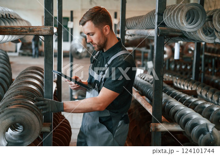 Checking details. Man in uniform is in workstation developing details of agriculture technique Checking details. Man in uniform is in workstation developing details of agriculture technique 124101744