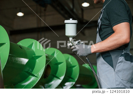 Painting details. Man in uniform is in workstation developing details of agriculture technique Painting details. Man in uniform is in workstation developing details of agriculture technique 124101810