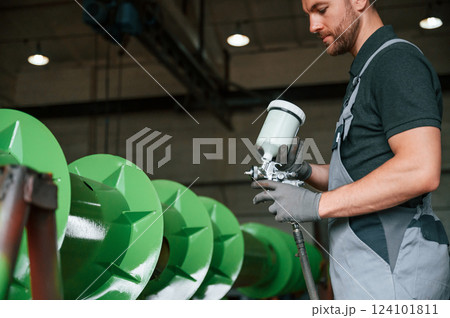Painting details to green color. Man in uniform is in workstation developing details of agriculture technique Painting details to green color. Man in uniform is in workstation developing details of agriculture technique 124101811