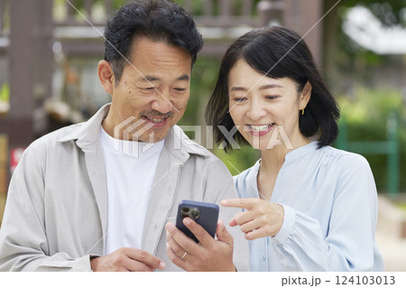 中年の夫婦　スマートフォンを使う　屋外 124103013