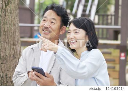 中年の夫婦 スマートフォンを使う 屋外 中年の夫婦 スマートフォンを使う 屋外 124103014