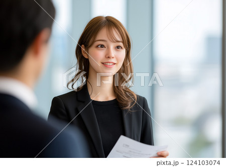 黒いスーツを着たプロフェッショナルな若い女性が、自信を持って契約書を提示している 124103074